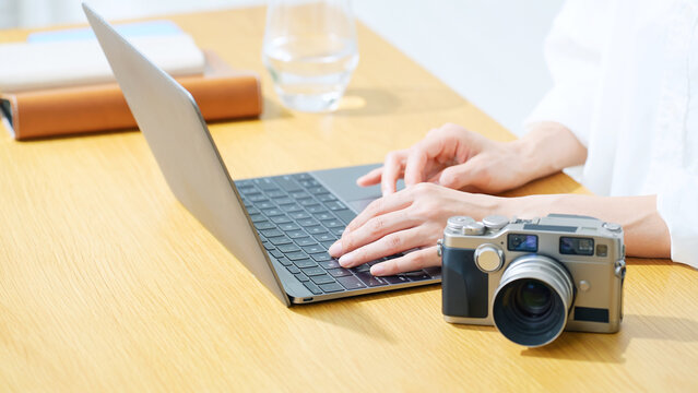 A woman using a camera and a laptop. Photography, editing, shooting, photographer, female photographer, image processing, auctions, listing items.