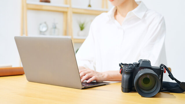 A woman using a camera and a laptop. Photography, editing, shooting, photographer, female photographer, image processing, auctions, listing items.