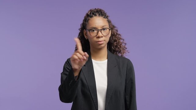 Confident young african woman raising a finger to signal "enough." College student girl expressing boundaries, refusal, authority and self respect with a serious look.