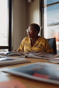 African american woman reading book in office. Professional interior designer looking at portfolio. Creative work process in studio. Inspiration and focus for business project.