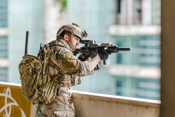 Fototapeta premium Military tactical operator holds rifle while clearing abandoned concrete building interior