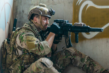 Fototapeta premium Military tactical operator holds rifle while clearing abandoned concrete building interior