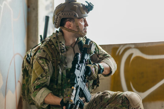 Military tactical operator holds rifle while clearing abandoned concrete building interior