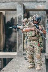 Fototapeta premium Military tactical operator holds rifle while clearing abandoned concrete building interior