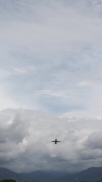 jet aircraft moves above mountains and layered clouds during its descent, showing international air travel, airport arrival and a scenic approach over the coastline