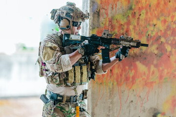 Fototapeta premium Military tactical operator holds rifle while clearing abandoned concrete building interior