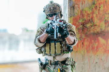 Fototapeta premium Military tactical operator holds rifle while clearing abandoned concrete building interior