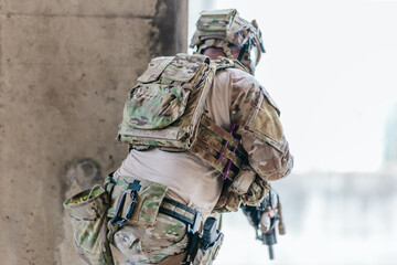 Obraz premium Military tactical operator holds rifle while clearing abandoned concrete building interior