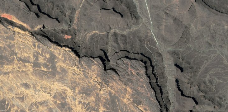 Aerial view of a dense channel network across folded desert terrain in the Sahara Desert North Africa showing intricate badlands erosion.