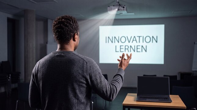 Mann gestikuliert &uuml;ber die Schulter zur Projektion mit Schriftzug Innovation Lernen im dunklen Seminarraum
