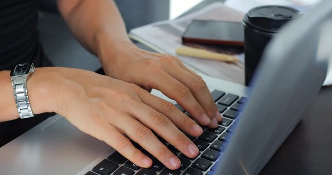 Casual work session with coffee and notes. Person using laptop in cafe environment with watch and journal. Individuals engaged in studying and notetaking at cozy cafe table with drinks