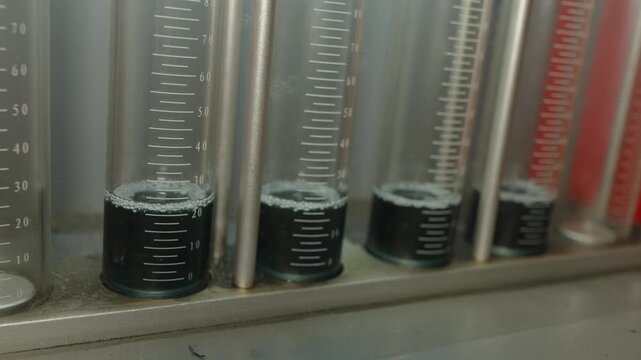 Close-up of glass graduated cylinders on a fuel injector testing diagnostic bench.