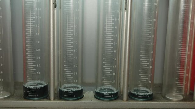 Close-up of glass graduated cylinders on a fuel injector testing diagnostic bench.