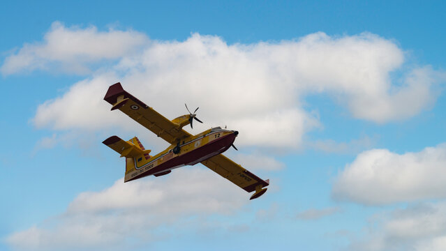 Canadair CL-415 Firefighting Aircraft Flying Under a Cloudy Blue Sky