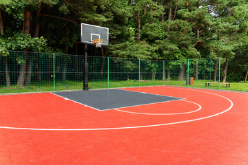 Naklejka premium Outdoor basketball court in a park. Empty sports ground for streetball and recreation.
