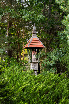 Small wooden shrine in a forest. Traditional religious wayside chapel in nature.