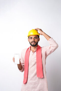 young indian construction worker showing smartphone screen standing on white background