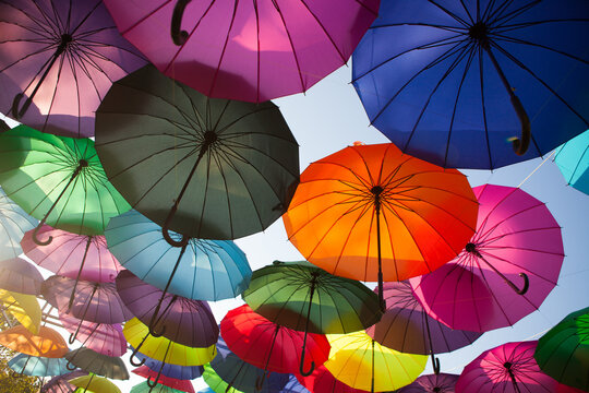 Colorful umbrellas suspended across an outdoor street display, vibrant decorative installation, creative background, summer festival.