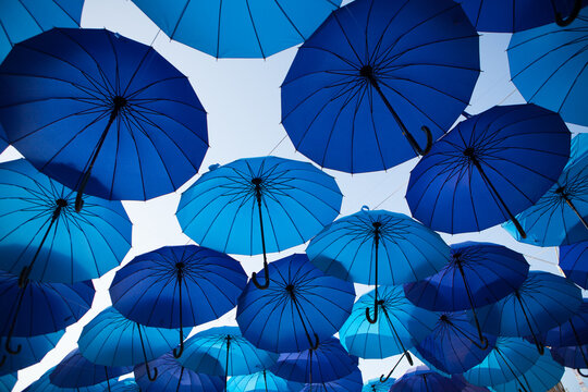A wide arrangement of blue umbrellas creates a repeating pattern in the open air, vibrant decorative installation, creative background.