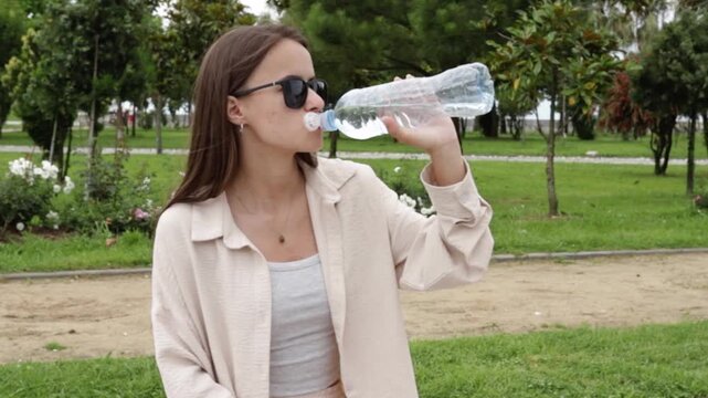 teenager opens a water bottle while resting on a park bench, promoting hydration breaks and practical heat safety during summer outdoor activities for an active youth lifestyle