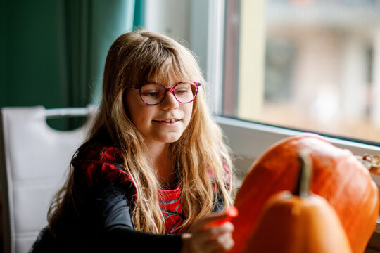 Little girl and big pumpkin for Halloween. Child making jack-o-lanterns