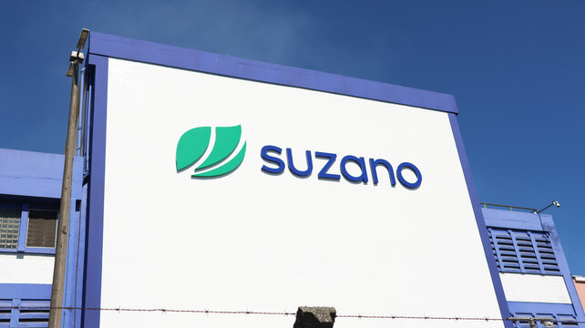 Grande painel com logotipo da Suzano instalado na fachada de unidade industrial, destacando a marca corporativa sob c&eacute;u azul, fotografado em S&atilde;o Paulo, SP, Brasil, em 10 de julho de 2026