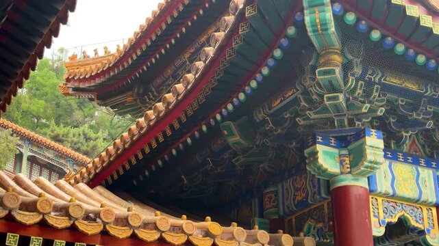 Traditional Chinese temple roof architecture with ornate golden tiles. View of historic palace eaves and intricate building details. Cultural heritage and ancient monument design concept in China.