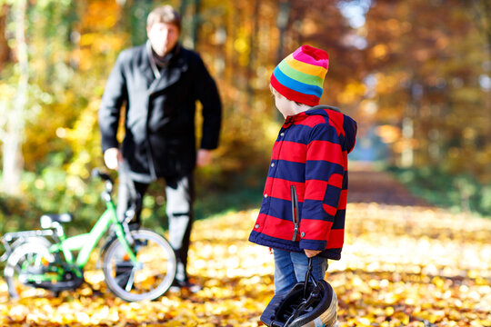 Little kid boy and father with bicycle in autumn forest