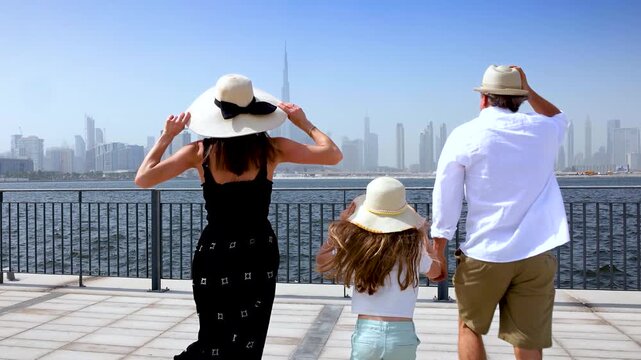 A excited tourist family on their city vacations runs towards a viewpoint of the skyline of Dubai, UAE