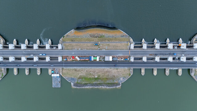Top down drone view of the Lorentzsluizen on the Afsluitdijk in the Netherlands. Infrastructure image showing sluice gates, road traffic, water barriers, lock structures and Dutch water management.