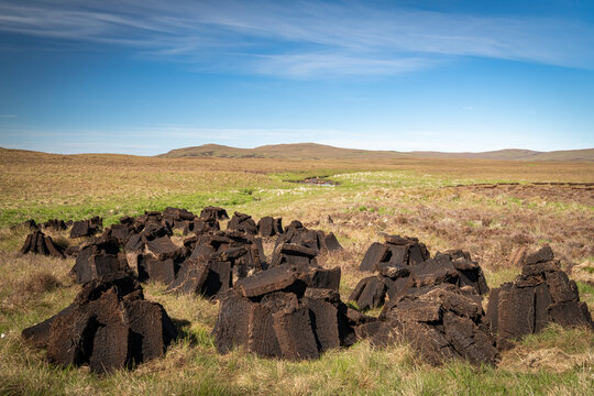 A warm, sunny HDR landscape image of freshly dug peat drying in the summer sunshine in Strathnaver, Sutherland, Scotland