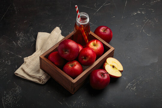 Red apples bottle apple juice straw wooden box rustic black background autumn fruit