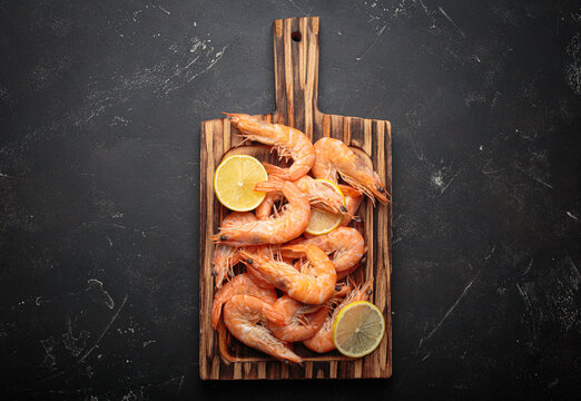 Cooked boiled shrimps lemon slices cutting board seafood dark background appetizer snack