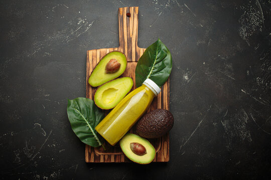 Avocado smoothie fresh fruit halves dark background cutting board healthy drink diet nutrition