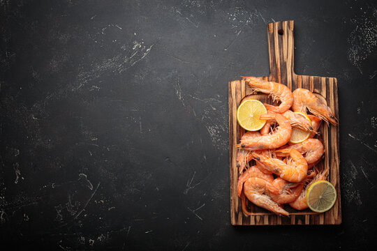 Cooked boiled shrimps lemon slices cutting board seafood dark background appetizer copy space