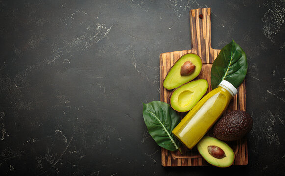 Avocado smoothie fresh fruit halves dark background cutting board healthy drink diet nutrition copy