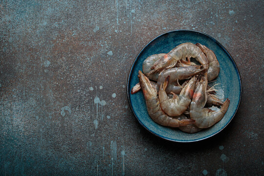 Fresh raw shrimps prawns plate dark background seafood uncooked copy space