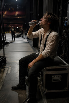 A solitary man takes a break in a dimly lit industrial setting, emphasizing his quiet contemplation and the functional environment.
