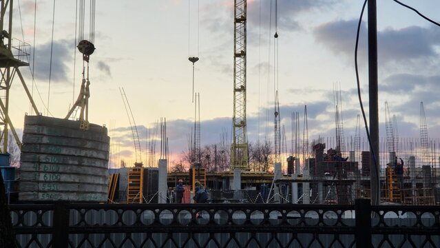 Construction site showing workers and machinery at sunset in an urban area
