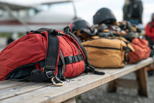 Close-up of parachute backpack and safety equipment on wooden bench before jump, premium product photography, no branding.