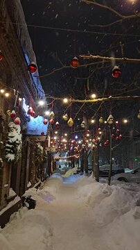 Winter night walk on a decorated street in a city with snow and lights