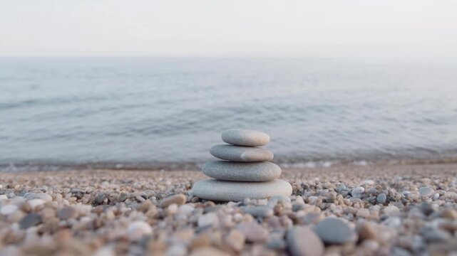 Stacked smooth stones on pebble beach with calm ocean water and serene horizon for relaxation and mindfulness