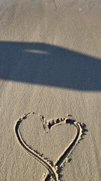 Person points at a small structure in the sand by the ocean during daylight
