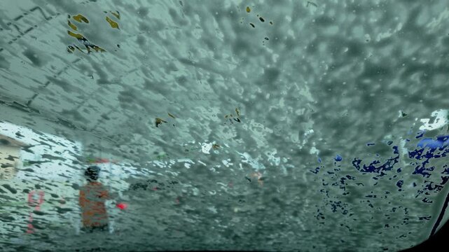 Soapy water covers car windshield during wash cycle
