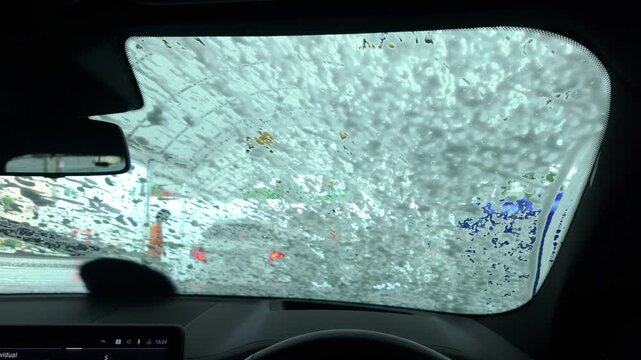 Car windshield being washed with soap at an automatic car wash station