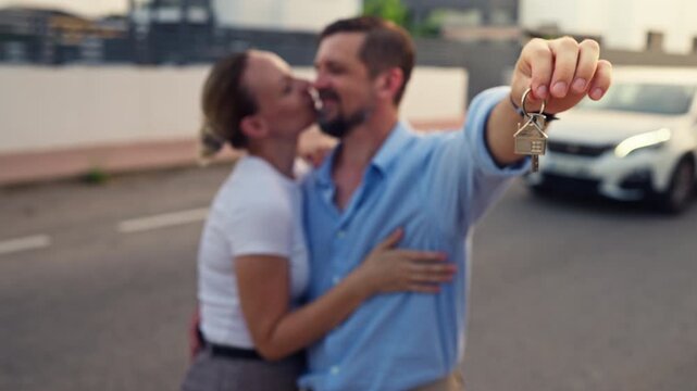 Happy couple celebrate new chapter in life by kissing and holding house keys outside their new home, enjoy fresh start, shared dreams, future plans, love, happiness, and togetherness