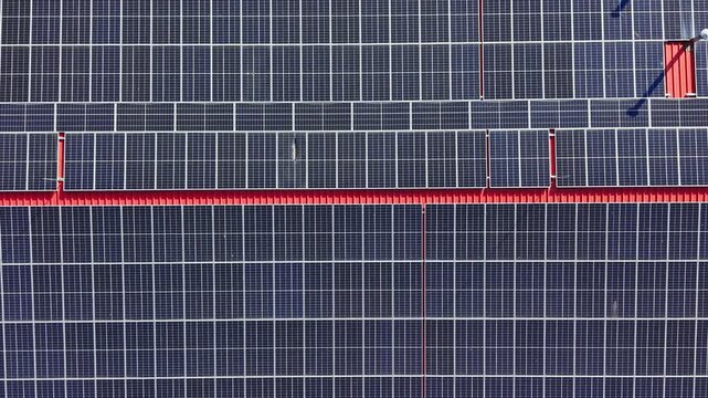 Rooftop covered with solar panels installed in a sunny area. The panels have a grid pattern and contribute to energy supply. Installation shows advancements in renewable energy.