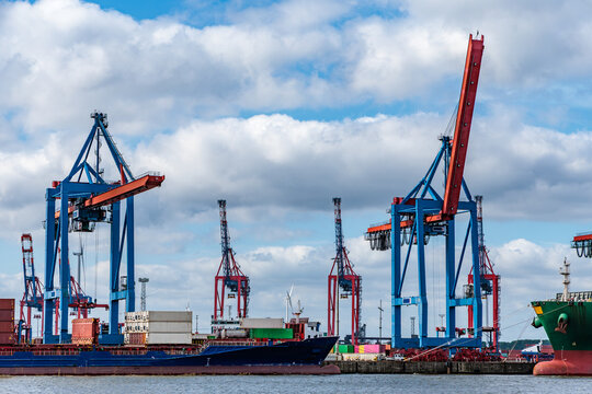 Container Cargo Ships and Gantry Cranes at a Commercial Seaport Terminal Under Dramatic Cloudy Sky