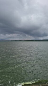 Calm water and gray clouds over the river at midday