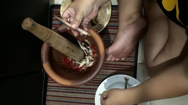 Person cleaning and preparing fish using a mortar and pestle